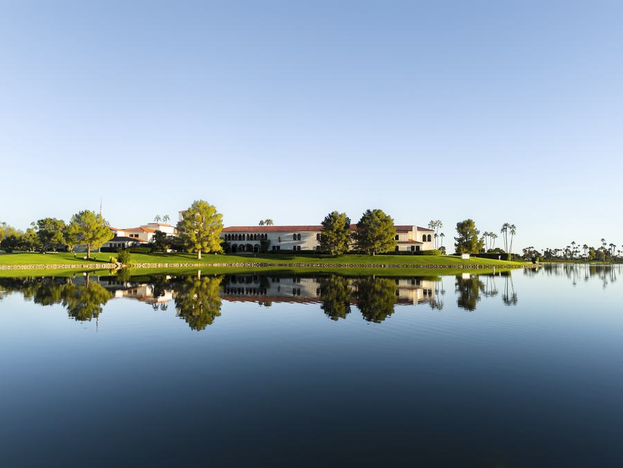 Clubhouse mirrored in still water on a golf course at golden hour
