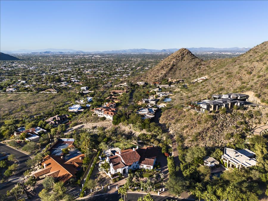 Aerial view of custom homes built into a desert hillside with the valley beyond