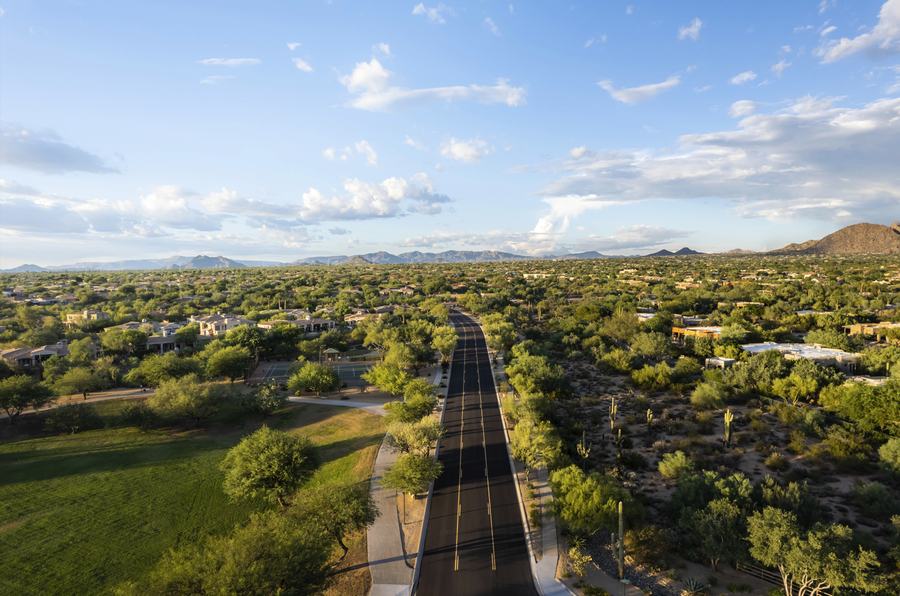 Aerial view down a road corridor through a master-planned desert community