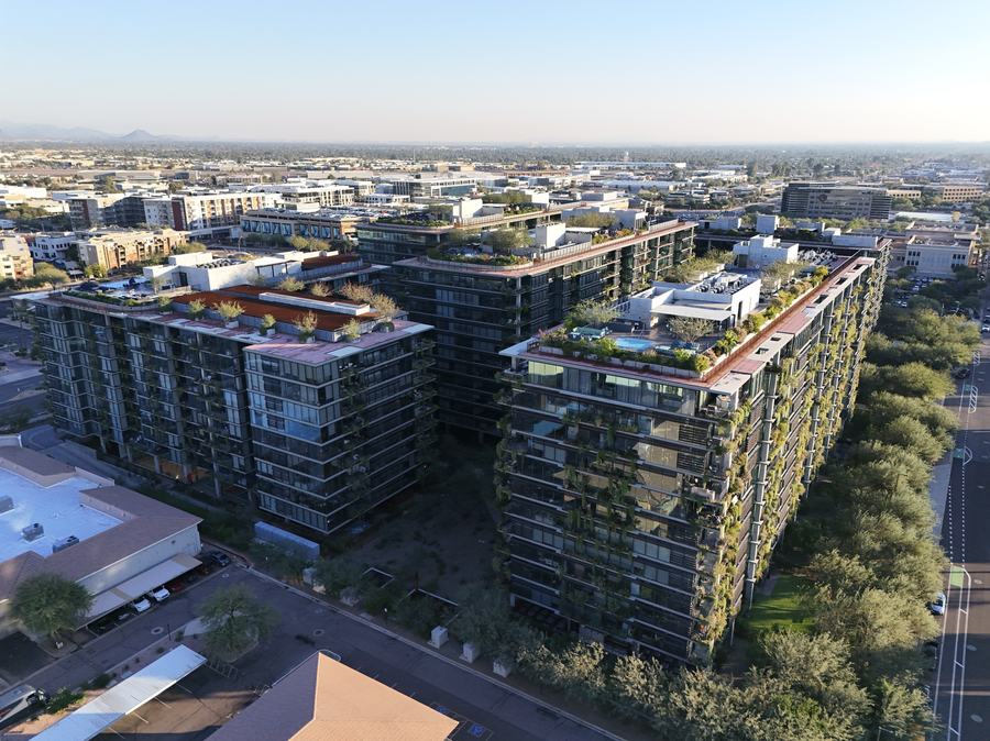 Aerial view of completed mixed-use residential towers with planted terraces and rooftop amenity decks