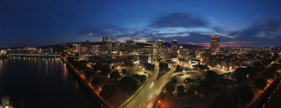 Wide panoramic aerial of a riverfront downtown skyline at blue hour
