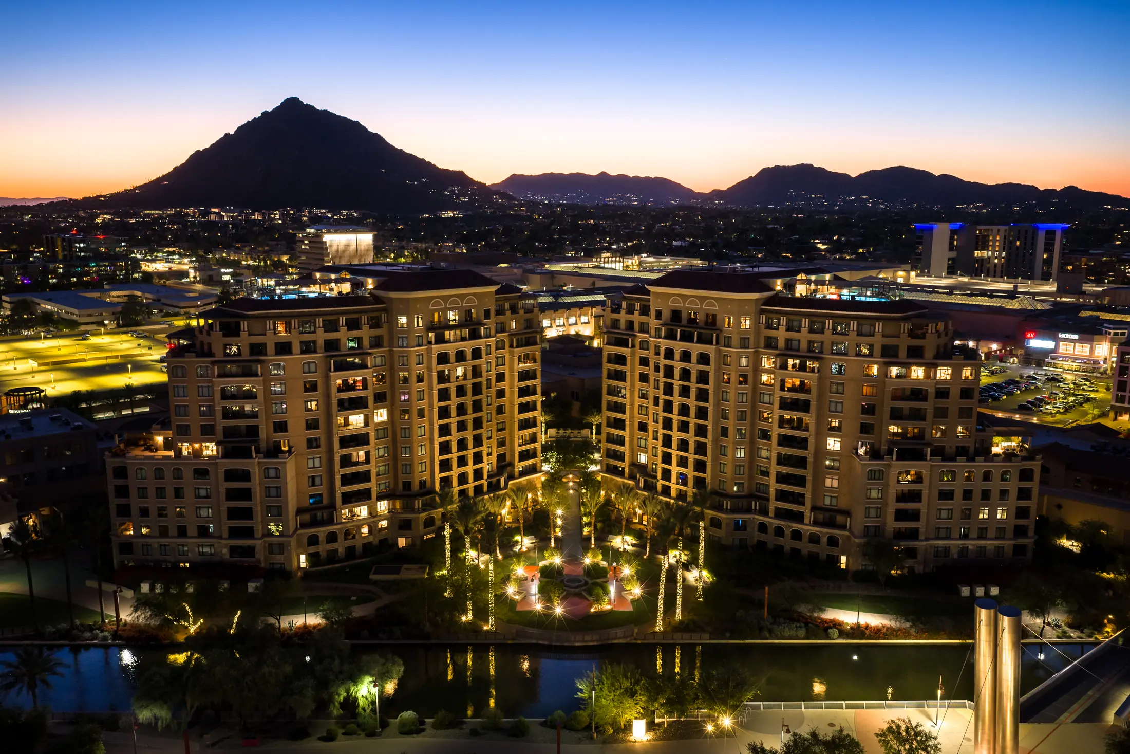 Completed mixed-use residential towers with lit courtyard at twilight